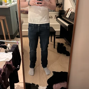 Mörkblå jeans från Replay ”Anbass” - Snygga mörkblå jeans från Replay med en klassisk femficksdesign. De har en knappgylf och är i en slim passform som ger en modern look. Perfekta för en stilren vardagsoutfit.