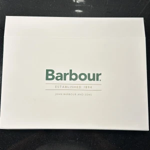 Halsduk från Barbour - Säljer en stilren rutig halsduk från Barbour i dova färger som blå, brun och grå med inslag av rött och gult. Halsduken är tillverkad i 100% ull och har fransar i ändarna. Perfekt för att hålla sig varm under kyliga dagar. Med matchande handskar som säljs i ett sett, inget av produkterna är någonsin använda så helt nya!😃