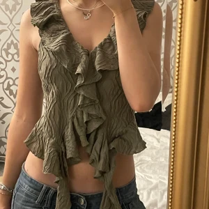 Olivgrön volangtopp från Zara - Säljer en olivgrön topp från Zara med volangdetaljer. Går att knyta längst ner också:)