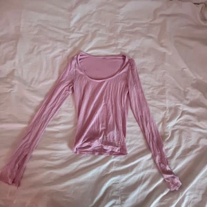 Rosa långärmad topp - Säljer en söt rosa långärmad topp med rund halsringning. Perfekt för en avslappnad stil. Toppen är gjord i ett mjukt material som känns skönt mot huden. Litet hål på en av armarna 