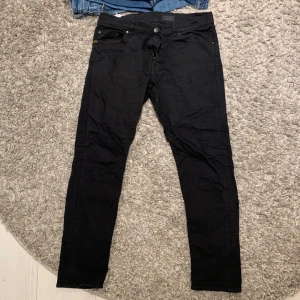 Svarta jeansbyxor från Forever - Snygga svarta jeansbyxor från Tiger of sweden  med en klassisk design. Byxorna har en knapp och dragkedja framtill samt fem fickor. Perfekta för en stilren look. 