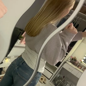 Ljuslila stickad kofta  - Koftan har långa ärmar och en öppen design utan knappar. .