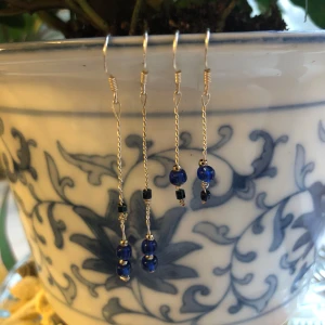 Egengjorda långa silverörhängen med blå pärlor  - Två par handgjorda silverörhängen av mig. Båda med silverkrokar i äkta silver med olika blåa pärlor. Lätta och ger en superfin detalj🌸 Priset är för båda 2 tillsammans!