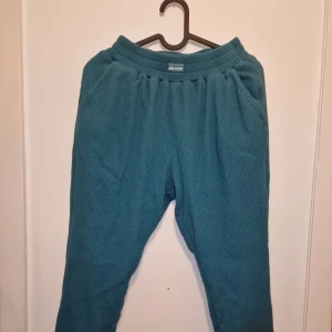 Turkosa ribbade mjukisbyxor från Bo+Tee - Säljer ett par turkosa mjukisbyxor från Bo+Tee i storlek XS. Byxorna har en ribbad struktur och elastisk midja för extra komfort. Perfekta för en avslappnad stil. Tvättade men ej använda därav säljes det. Garderobsrensning så kika gärna på övriga auktioner. 