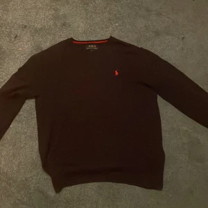 Mörk blå tröja från Polo Ralph Lauren - Säljer en stilren mörk blå tröja från Polo Ralph Lauren med det klassiska röda logotypen på bröstet. Tröjan har långa ärmar och en rund halsringning. Perfekt för en avslappnad och snygg look.