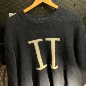 Mörkblå tröja från Les Deux - Säljer en stilren mörkblå tröja från Les Deux med en stor vit logotyp på framsidan. Tröjan har en rund halsringning och är tillverkad i ett mjukt material som passar perfekt för kyligare dagar. Sitter mer som L. Finns bilder med den på vid förfrågan!