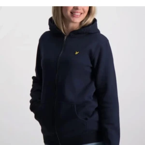 Lyle & scott hoodie - Säljer en mörkblå hoodie från Lyle & Scott med dragkedja och en liten gul logga på bröstet. Perfekt för en avslappnad stil. Den har långa ärmar och en bekväm passform. Var barnstorlek 12-13 men passar mig som har Xs-S