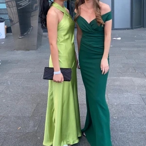 Grön långklänning med halterneck - Limegrön långklänning med halterneck-design i satin likande material. Den är hemma sydd och passar en som har storlek XXS och jag är 163cm och hade 7 cm klackar som referens. 