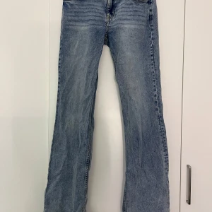 Blå bootcut jeans - Snygga lågmidjade blå bootcut jeans med klassisk femficksdesign och knappgylf. Perfekta för en avslappnad stil. De har en lätt tvättad look som ger en vintage känsla. Finns ingen lapp men tror storleken är 40 och märket är h&m 