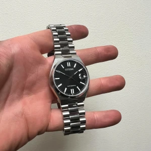 Citizen Tsuyosa automatisk klocka - Snygg Citizen automatisk klocka med svart urtavla och datumvisning. Klockan har en stilren design med silverfärgad boett och armband i rostfritt stål. Perfekt för den som söker en tidlös accessoar. Extra länkar till kommer. Nypris: 3100kr. Skick 9/10.  40mm.