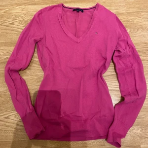 Rosa v-ringad tröja från Tommy Hilfiger - Säljer en snygg rosa v-ringad tröja från Tommy Hilfiger. Tröjan har långa ärmar och är tillverkad i bomull, vilket gör den både bekväm och stilren. Perfekt för en avslappnad look. 💖säljer den för lågt pris då jag vill bli av med den💕