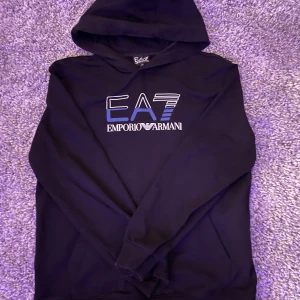 Svart hoodie från Emporio Armani - Säljer en stilren svart hoodie från Emporio Armani med EA7-logga på bröstet. Den är använd ett par gånger men hade fortfarande sagt att den är i bra skick. Storleken är 168/XL. Det är bara att skicka om ni har några frågor. Priset är inte fast hade kunnat gå ner