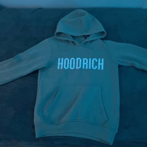 Grå hoodie från Hoodrich - Säljer en snygg grå hoodie från Hoodrich med stor vit logga på bröstet. Tröjan har en klassisk känguruficka och en bekväm huva. Den har absolut inga skador och har inte använt den så mycket, därför säljer jag den. Priset kan diskuteras så hör av er 