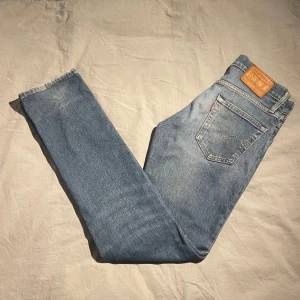 Blå jeans från Levi's - Snygga Levis 511 jeans i blå denim med klassisk femficksdesign och en liten reva på benet för en cool, sliten look. Perfekta för en avslappnad stil. Skicket är väldigt bra 9/10  Mått: Längd: 106 Bredd: 38 Byxöppning: 17