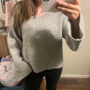 Grå stickad tröja - Mysig grå stickad tröja med lång ärm och avslappnad passform. Perfekt för kyligare dagar och enkel att matcha med olika outfits.