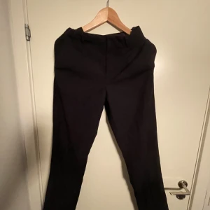 Svarta kostymbyxor - Snygga svarta kostymbyxor med en klassisk passform. Perfekta för en stilren look. Byxorna har en rak design och är tillverkade i ett elegant material.