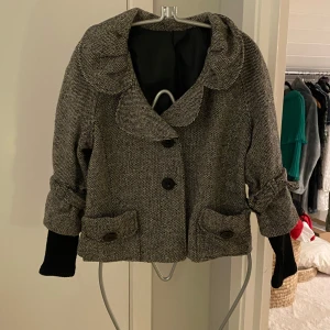 Superfin grå jacka / kappa! XS - Säljer en superfin grå kappa med stora knappar och en elegant krage. Den har en chic, vintage vibe med sina uppvikta ärmar och två stora fickor fram. Perfekt för höst och vår när du vill se stilren ut. Passar till både vardag och fest! Otroligt vacker och coolt plagg!  2 fickor fram!  Vet tyvärr ej märke Insydda torgvantar/låtsas långtröja  Knapparna är helt fantastiskt häftiga! ( nästan 3 cm)  Det är ull i jackan!