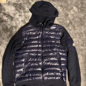 Moncler Cardigan  - Hej! Säljer nu en Moncler Magila Con Cappuccio cardigan i Storleken 4 motsvarande L. Har inget og därav priset! Jackan har tecken på användning men inga större flaws. Nypris ca 10 000kr Mitt pris 2500kr. Priset ej hugget i sten! Hör av dig vid fundering!
