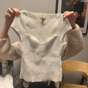 Beige ribbad topp - Säljer en stilren beige ribbad topp med korta ärmar och v-ringad design. Perfekt för en chic och avslappnad look. Passar bra till både jeans och kjol.