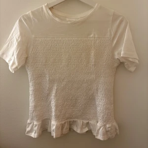 Vit kortärmad topp med volangdetalj - Säljer denna tröja pågrund av att den inte används längre. Den är i storlek 158/164 men passar mig som är xs/s💕