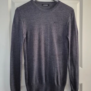 Grå tröja från J.Lindeberg - Grå tröja från J.Lindeberg i merinoullsblandning. Svart logotyp på bröstet. Mycket fint skick. Hör av er vid eventuella frågor eller funderingar. 