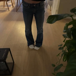 Blå lågmidjade bootcut jeans - ONLY - Snygga blå jeans med bootcut-stil och låg midja. Perfekta för en avslappnad look. Klassisk design med fem fickor och knappgylf. Lite för stor för mig men skulle se betydligt mycket mer låg midjat om den skulle passat perfekt! 