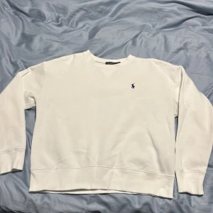  Ralph Lauren Tröja - En vit Ralph lauren tröja, bra skick använd ett par gånger. Det är en missfärgning vid armhålan på tröjan, blivit av tvätt medel men syns inte när tröjan är på.