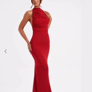 Röd långklänning med öppen rygg - Snygg röd långklänning med halterneck och öppen rygg. Klänningen har en tight passform och knytning i ryggen för en elegant look. Perfekt för bal eller liknande. Använd en gång. Köpt för 1000 + tullavgifter.