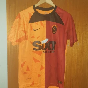 Galatasaray 2022/23. Nummer 99 Icardi - Snygg Galatasaray fotbollströja från Nike i orange och rött med korta ärmar. Tröjan har klubbens emblem på bröstet och sponsorlogga framtill. På baksidan finns spelarnamnet Icardi och nummer 99. Perfekt för fans som vill visa sitt stöd! Storlek M men sitter som S.