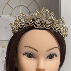 Elegant guldfärgad tiara med glittrande stenar - Vacker och elegant tiara i guldfärg, dekorerad med klara strass-stenar som ger en fin glans. Perfekt för bröllop, fester och fotograferingar.  🆕 Helt ny och oanvänd! hör av dig vid frågor!