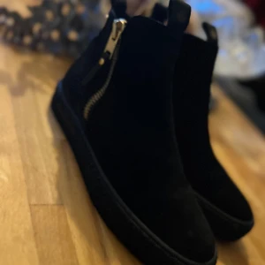 Svarta Canada Snow med dragkedja i guld  - Jag köpte dessa, hade de för ett event, sedan blev de glömda i garderoben och jag köpte ett par andra :-)  Nypris 1.800:- Foder i ullblandning som isolerar Värmande innersula med flera lager Yttersula av gummimix i crepe-modell  Leverantörens färgnamn: Black Vattentäta: Nej Varmfodrade: Ja Foder: Ull/syntet Yttermaterial: Skinn Vattenavvisande: Ja Membran: Nej Läst: Normal Skafthöjd: Medel