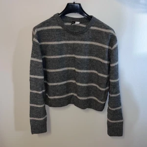 Grå randig tröja från H&M - Säljer en snygg grå tröja från H&M med vita ränder. Tröjan har en normal passform och långa ärmar, perfekt för kyligare dagar. Den är tillverkad i ett mjukt material som känns skönt mot huden.