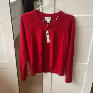 Snygg röd kofta från Holly & White med knappar framtill. Tillverkad i mjukt Tencel-material som ger en skön känsla. Perfekt för att lägga till en färgklick i garderoben. Passar bra till både jeans och kjol. (Köparen står för frakt)