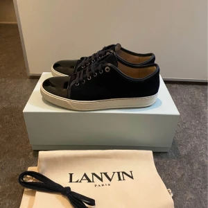 Lanvin Sneakers - Snygga svarta sneakers från Lanvin med vit sula och svarta snören. Skorna har en stilren design med en glansig tå och är perfekta för en trendig look. Storlek 43 Mvh