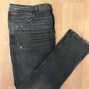 Mörkblå jeans från Hugo - Snygga mörkblå jeans från Hugo med slitna detaljer och en klassisk femficksdesign. Jeansen har en rak passform . Perfekta för en avslappnad stil.