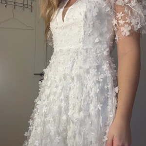 Vit klänning- Studentklänning - Säljer en vacker vit klänning med blommigt mönster och korta ärmar. Klänningen var tänkt som studentklänning men hittade en annan och säljer därför denna dröm. Klänningen är helt oanvänd, med lappar kvar. Inköpt för 999kr! 💖Är vanligtvis en 36 (S) men denna passar fortfarande jättebra! 