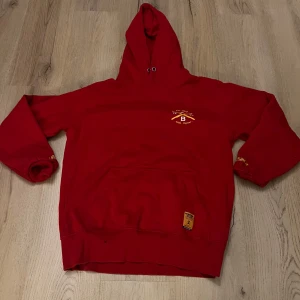 Röd hoodie med tryck - Snygg röd hoodie med tryck på både fram- och baksidan. Framsidan har en liten logga medan baksidan har ett större tryck med texten 'Eat Sleep Ride Repeat' och årtalet 1992. Perfekt för en avslappnad stil.