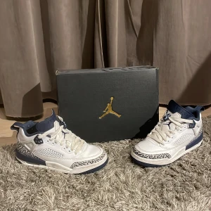 Nike Air Jordans Spizike Low - Snygga Nike Air Jordans Spizike Low i vitt och blått med ikoniskt mönsterdetalj. Skorna har snörning och en unik design som kombinerar flera klassiska element. Perfekta för sneaker-entusiaster som vill ha något speciellt.