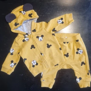 Nytt brnset med Musse Pigg-mönster - Söt gul hoodie med byxor för barn med Musse Pigg-mönster. Tröjan har en dragkedja och huva med små öron. Tillverkad i bomull och polyester för en mjuk och bekväm känsla. Disney by HM