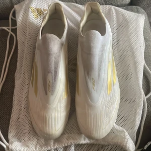  Adidas F50 Elite fotbollsskor - Säljer ett par stilrena vit guldiga Adidas F50 ELITE laceless. Fungerar på konstgräs och på naturgräs. Använt dessa i endast 1 månad. Ordinarie pris 3149 på Unisport. Storlek 44, UK 9,5 eller US 10,5. Lägre pris kan diskuteras.