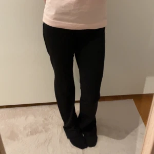 Svarta byxor med fickdetaljer - Snygga svarta byxor med knapplås på bakfickorna. De har en klassisk design och passar perfekt för en stilren look. Byxorna har en rak passform och är tillverkade i ett bekvämt material.