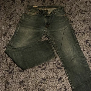 Levi's jeans i mörk tvätt - Säljer ett par klassiska Levi's jeans i mörk tvätt. De har en rak passform och är tillverkade i slitstarkt denim. Perfekta för en avslappnad stil. Jeansens ikoniska läderpatch syns baktill.