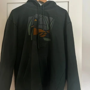 Grön hoodie från Carhartt - En mycket bekväm Hoodie från carhartt. Den e stilren och prydlig och passar till det mesta. Knappt använd köpte den för 1200 sek