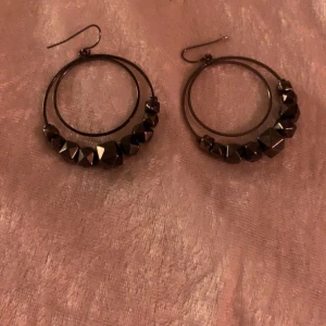 Svarta örhängen med pärlor - Snygga svarta örhängen i cirkelform med dekorativa pärlor. Perfekta för att ge en elegant touch till din outfit. De har en enkel krok för enkel användning.