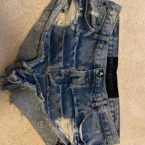 Blå jeansshorts från One Teaspoon stl 29 - Säljer ett par coola blå jeansshorts från One Teaspoon. De har en sliten look med fransiga kanter och slitningar. Shortsen har fem fickor och knappgylf. På sista bilden håller jag in dom då de tyvärr är för stora 💞