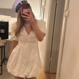 Vit kortklänning med puffärmar - Säljer en söt vit kortklänning med puffiga kortärmar och v-ringning. Klänningen har ett fint broderat mönster och en luftig passform som ger en romantisk känsla. Perfekt för sommarens alla tillfällen men speciellt studenten!! Aldrig använd jag köpte denna för ett dag sen men har nu hittat en ny. Hör gärna av dig om du har frågor!😊storlek xs. Köpt från Alborg Modehus.