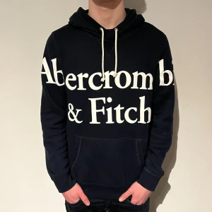 Abercombie & Fitch - Fet hoodie med stort tryck från Abercombie & fitch, tröjan är mörkblå och har en sjukt nice passform.