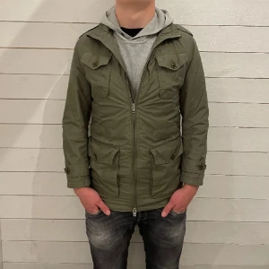  J.Lindeberg feildjacket - Snygg olivgrön jacka från J.Lindeberg med dragkedja och knappar. Jackan har flera praktiska fickor och en stilren design. Perfekt för höst och vår. Den är strl xs men sitter väldigt stort så den är runt S-M.
