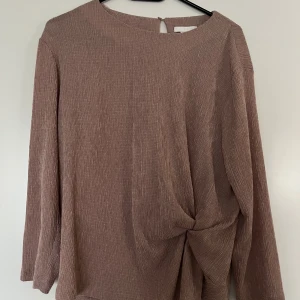 Tröja, H&M, L, rosa - Rosa tröja i fint material från H&M, storlek L. Tröjan är mycket fins skick, som ny. Stängning bak i nacken med en knapp. Fina sidodetaljer på framsidan. 74% polyester, 25% viskos och 1% elastan.  Mått:  Längd ca 60 cm Byst ca 52 cm Midja ca 47 cm Ärmlängd mätt från axeln ca 50 cm