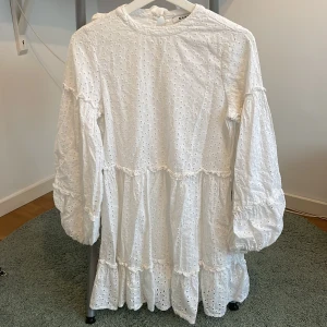 Vit kort klänning - En söt vit kort klänning. Lite puffärmar och volang detaljer. Fint skick. Kan skicka fler bilder vid intresse!